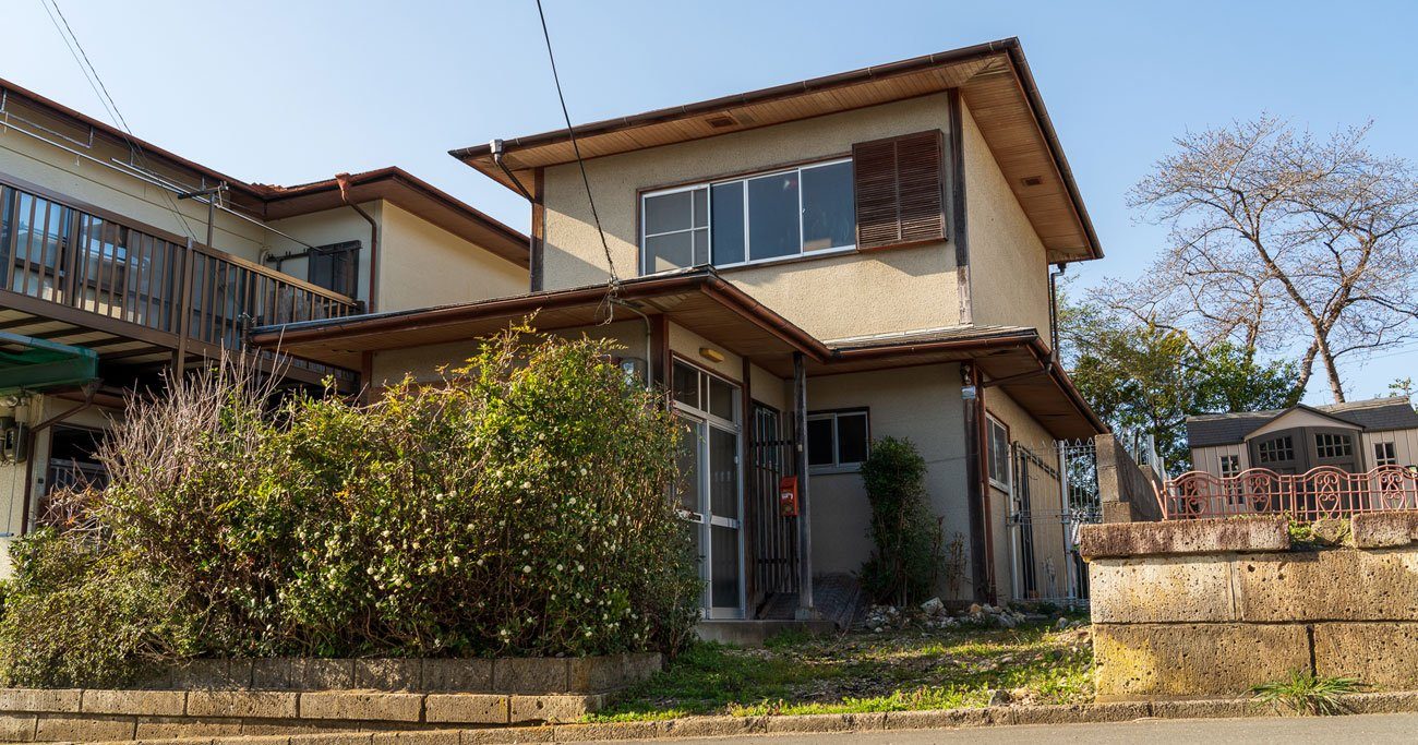 生垣が伸びたまま残る、昭和の木造二階建ての実家